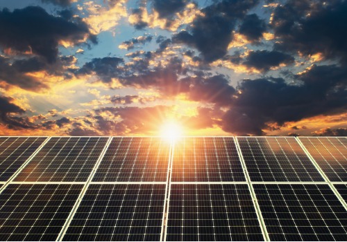 The sun rising behind solar panels collecting Solar Energy in Richmond VA