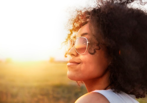 A woman smiles up at the sun. If you're looking for Commercial Solar in Central Illinois, The Sun Collectors can help you harness the power of the sun for your business.